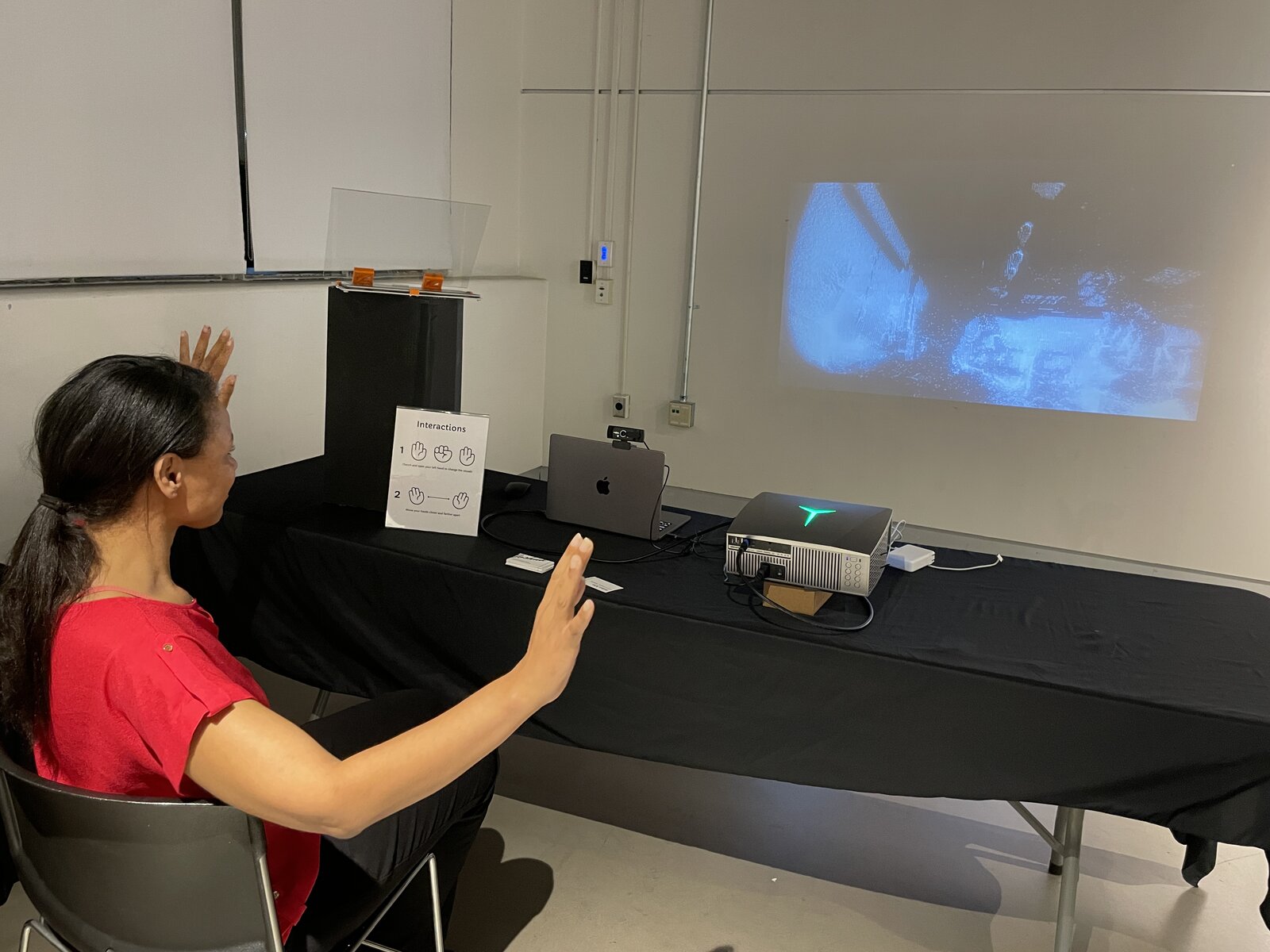A visitor seated, gesturing toward the projection